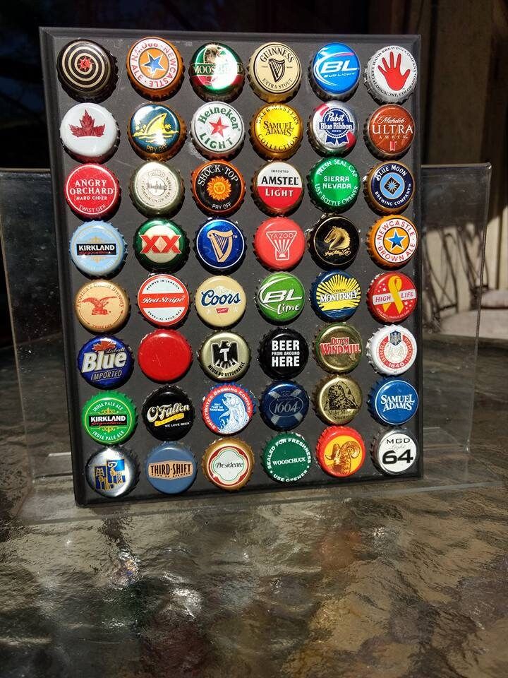 an assortment of beer bottle caps in a display case on a marble counter top,