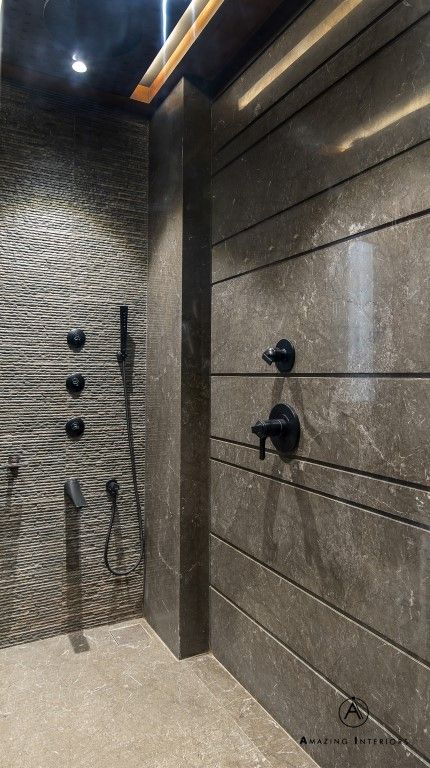 a bathroom with gray walls and black fixtures on the wall, along with an overhead shower head