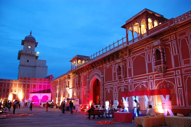 an outdoor event with people sitting and standing in front of the building at night time