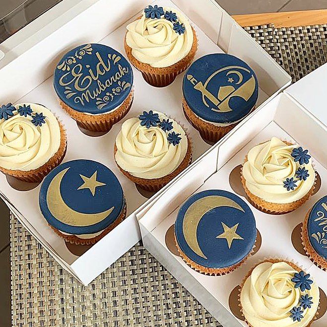 six cupcakes with blue and white frosting in a box on a table