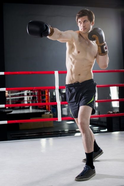 a shirtless man in shorts and boxing gloves