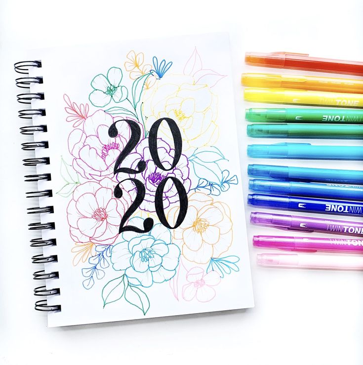 a spiral notebook with the number twenty two on it next to colored markers