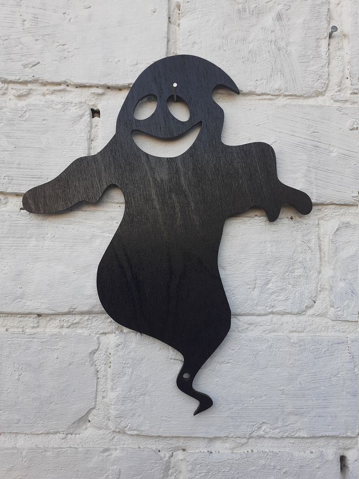 a metal cut out of a ghost hanging on a brick wall