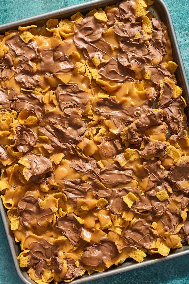 a pan filled with chocolate and peanut butter covered desserts on top of a blue table