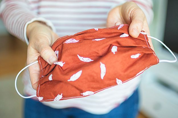 a woman holding a red bag with white leaves on it in front of a microwave