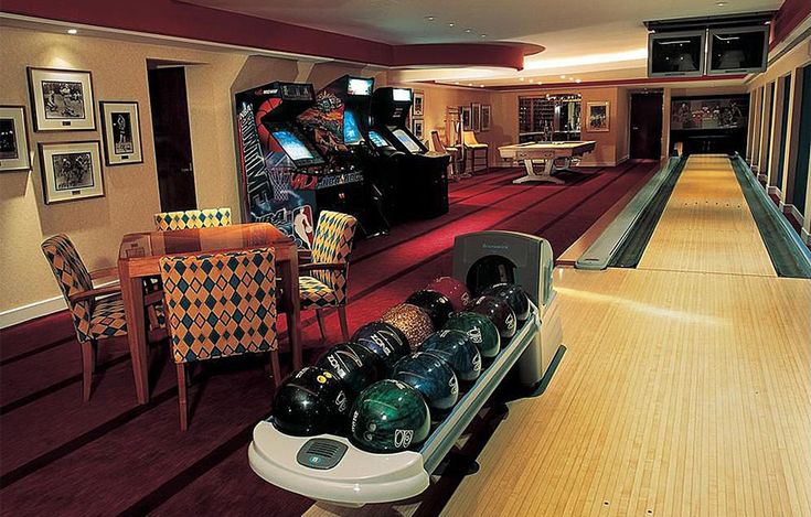 a bowling alley with several bowling balls on the side and two arcade games in the back