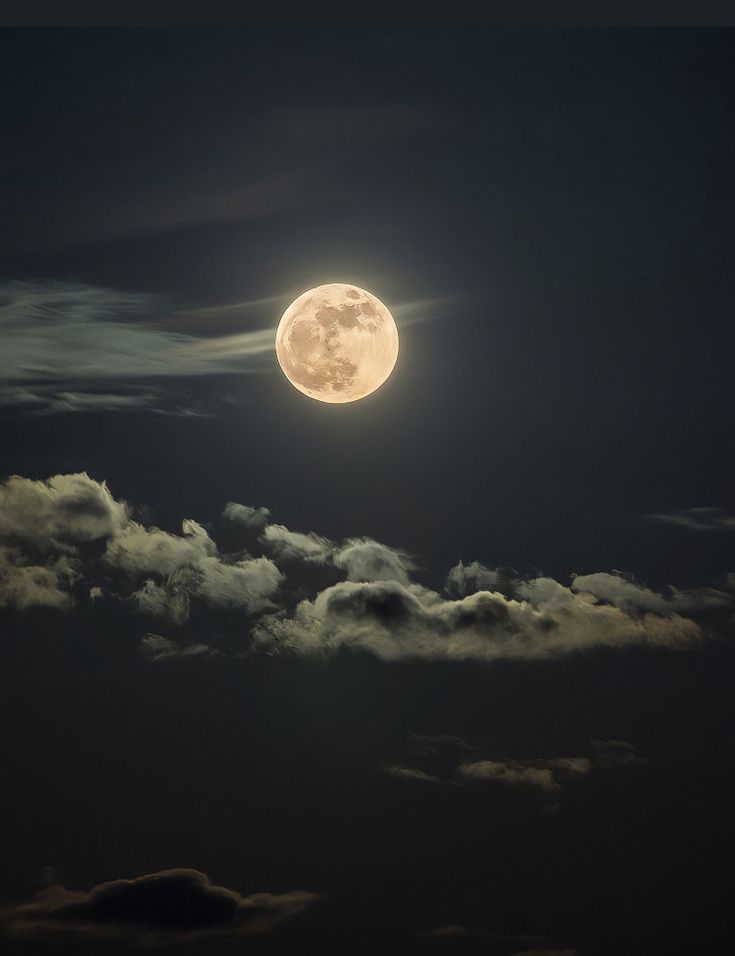 the full moon is shining brightly in the dark night sky with fluffy clouds around it