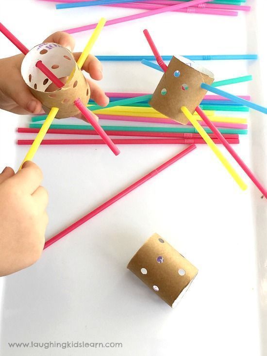 a child is playing with colored sticks and an object on the table next to them