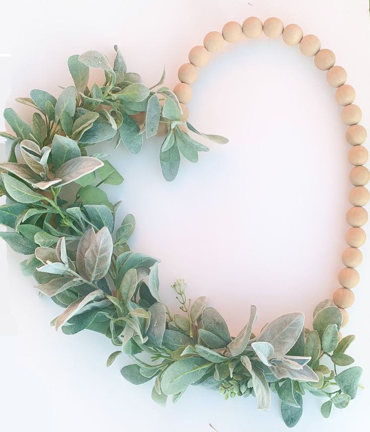 a wooden beaded necklace with green leaves and greenery on the front, against a white background