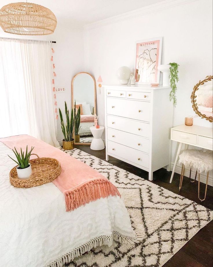 a bedroom with white furniture and pink accents on the walls, along with a large mirror