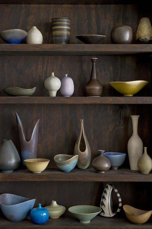 a shelf filled with vases and bowls on top of wooden shelves