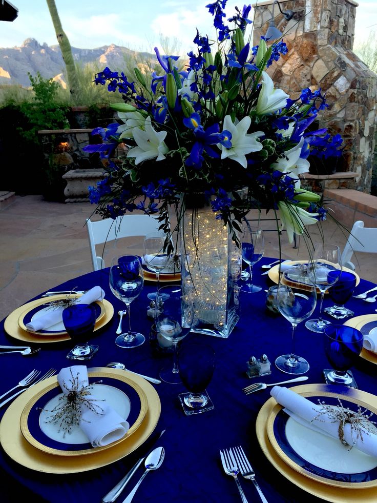 a table set with blue and white plates, silverware and flowers in a vase