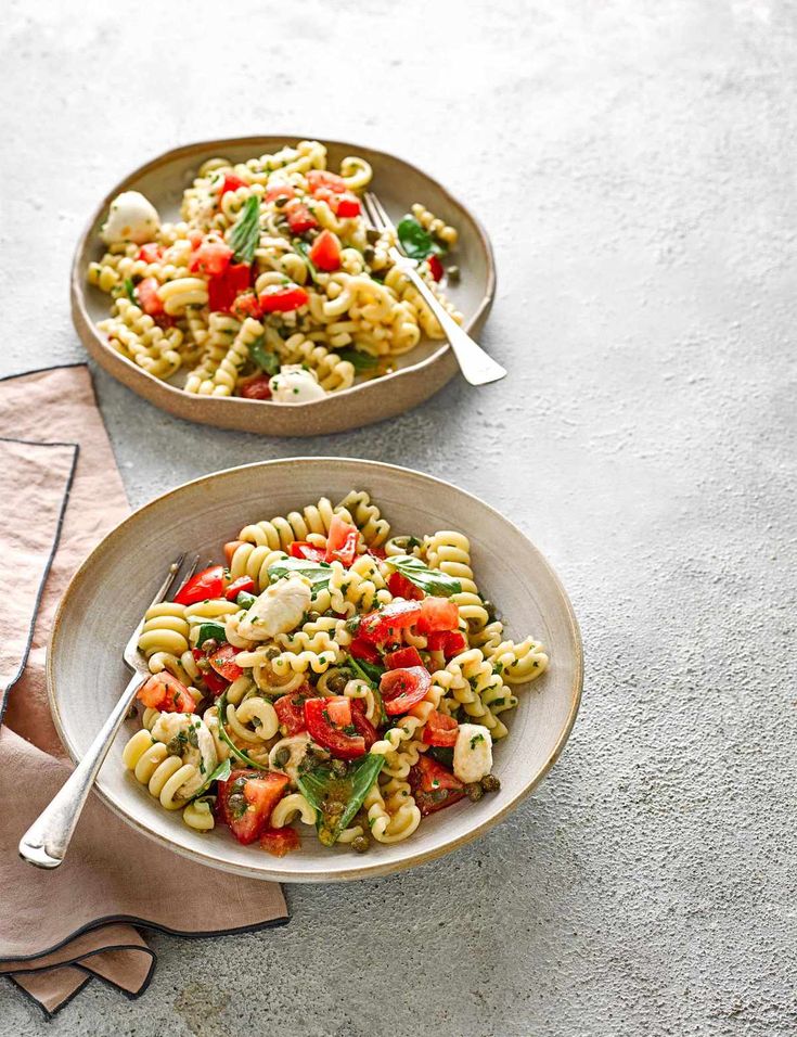 two bowls filled with pasta salad on top of a table