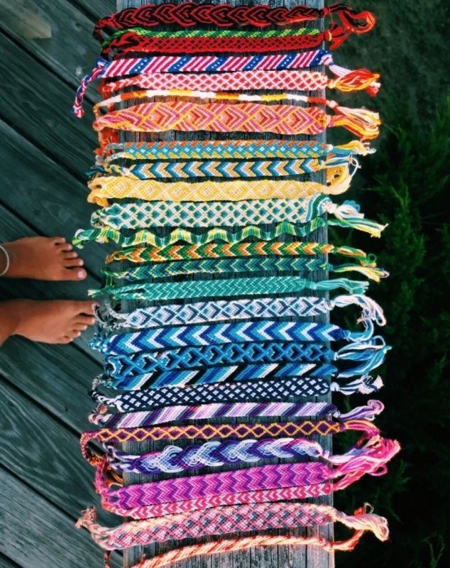 a person standing next to a pile of colorful bracelets