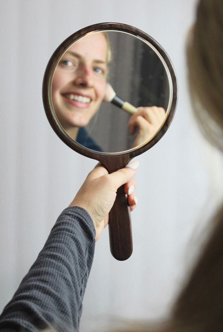 a woman looking at herself in the mirror with a toothbrush in her hand and brushing her teeth