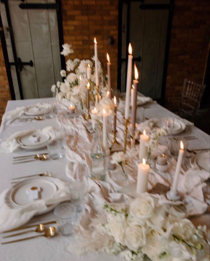 the table is set with white flowers, candles and napkins for an elegant dinner