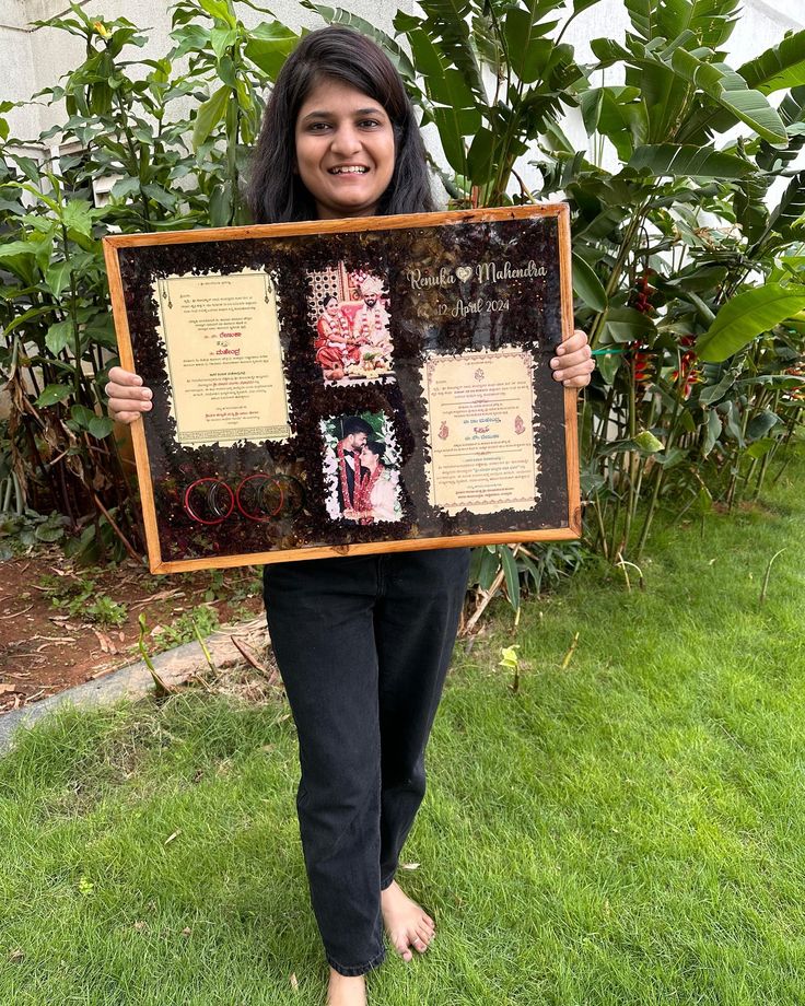 a woman standing in the grass holding up a framed plaque with some writing on it