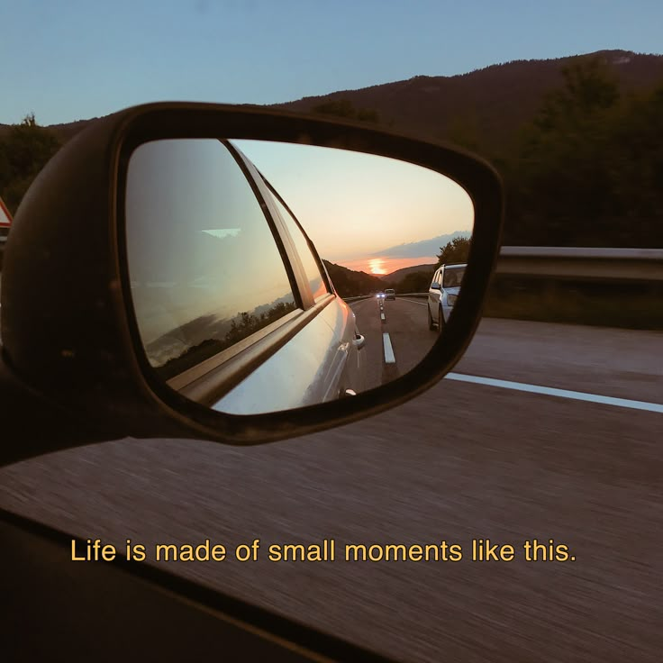 a car's rear view mirror reflecting the sunset