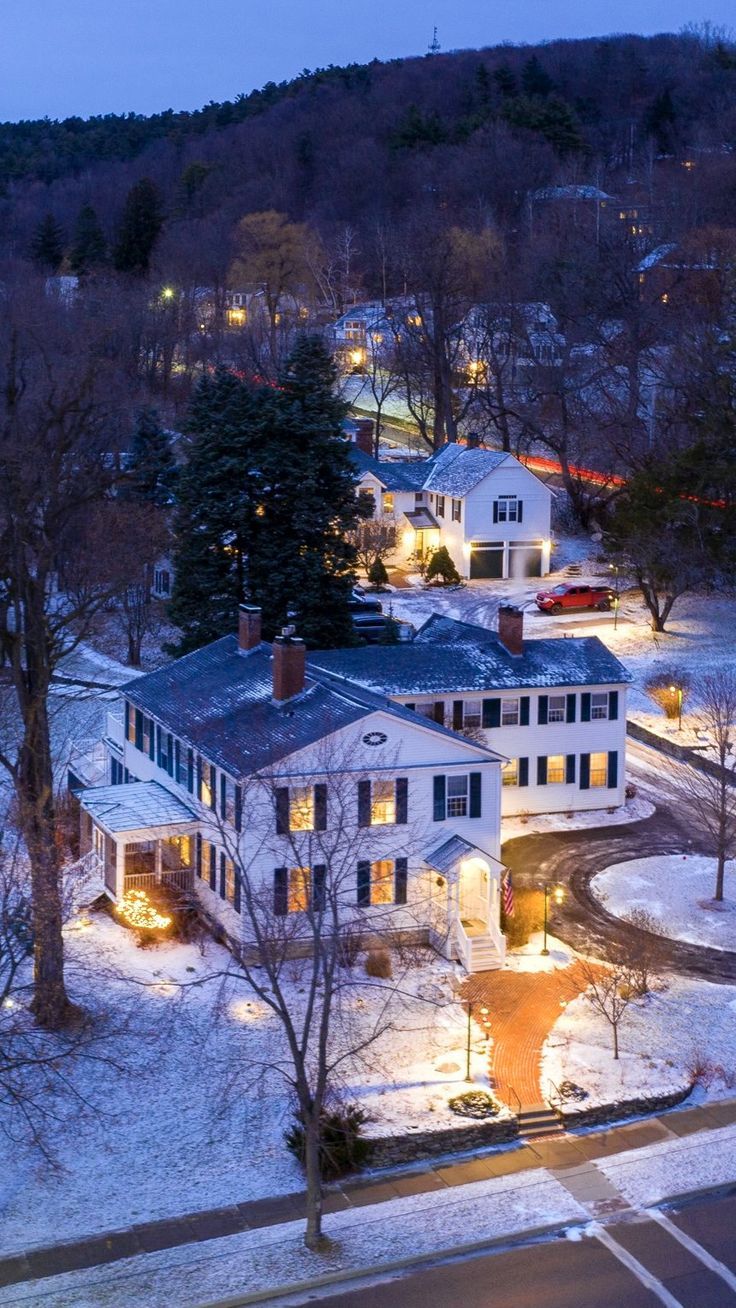 an aerial view of a large white house in the middle of winter with snow on the ground