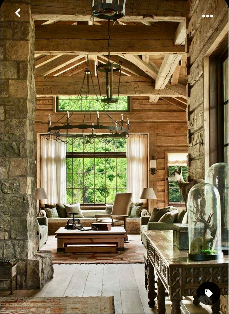 an open living room with stone walls and wood ceilinging, along with large windows