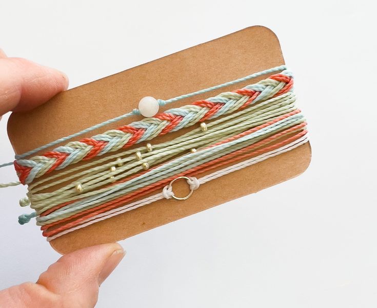 a person is holding a piece of paper with some string attached to it and two rings on the end