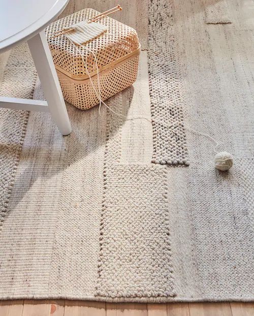 the rug is on the floor next to a table and chair with a basket in front of it