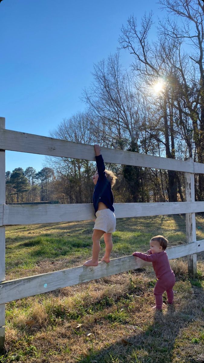 two small children are climbing on a fence