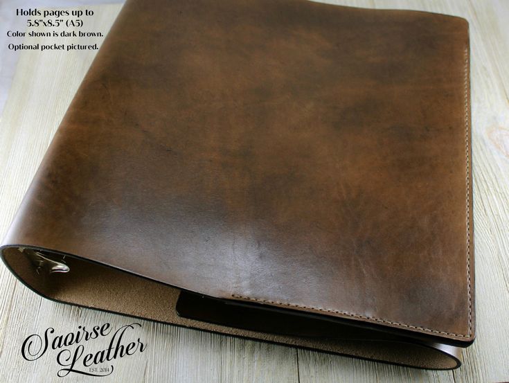 a brown leather notebook cover sitting on top of a wooden table