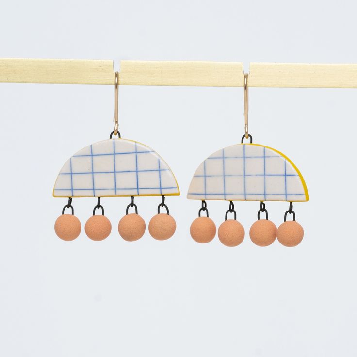 two surfboard earrings hanging from a clothes line with oranges and blue plaid on them