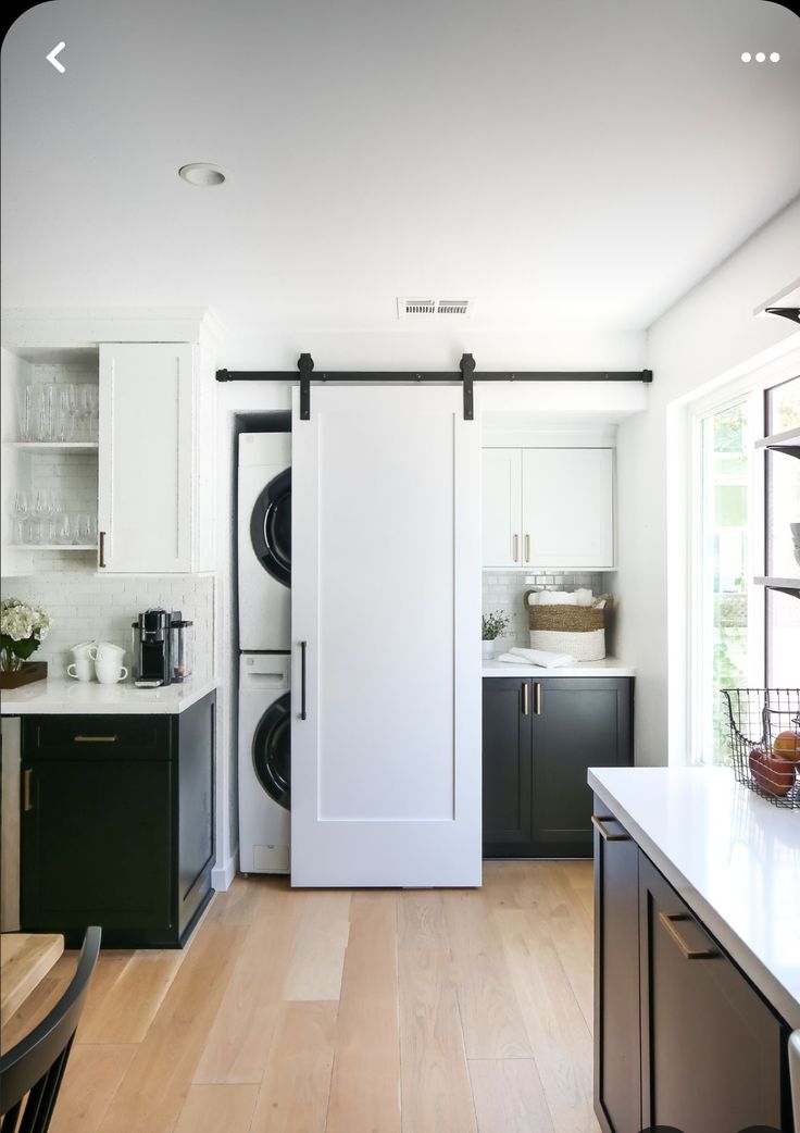 an open door leading into a kitchen with white cabinets and black appliances in the background