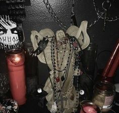 there is a statue with chains and candles on the table in front of it, surrounded by other items