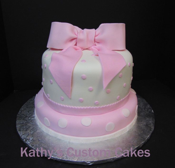 a pink and white polka dot cake with a bow on top