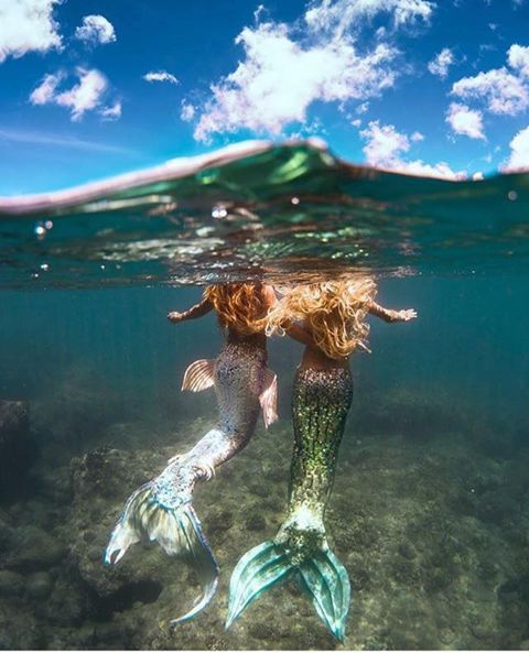 two mermaids are swimming in the ocean together