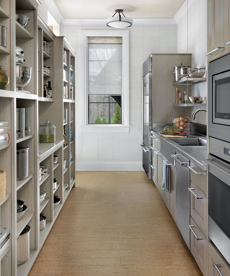 an empty kitchen with stainless steel appliances and shelves full of dishes on the counter top