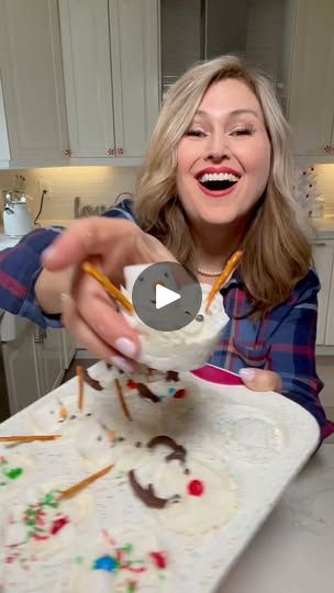 a woman is smiling and holding a spoon in her hand while she eats cake with icing on it