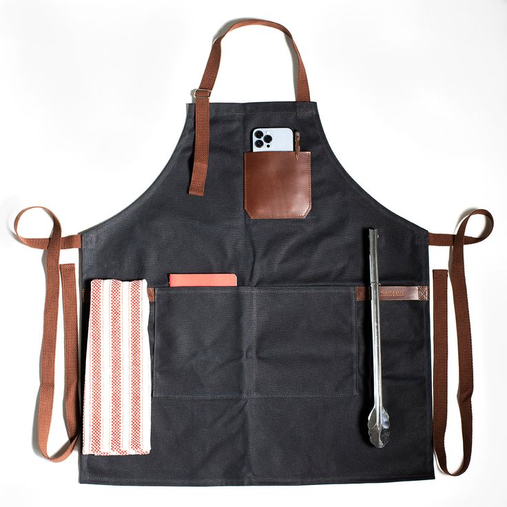 the apron is black with brown straps and has two pocket pockets on one side, an orange stripe in the other