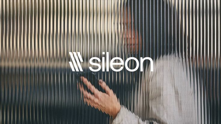 a man looking at his cell phone while standing in front of a wall with the word sieon on it