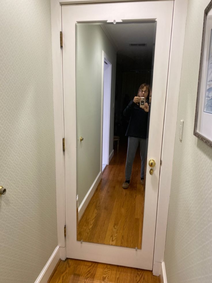 a woman taking a selfie in front of a mirror on the door way to her home