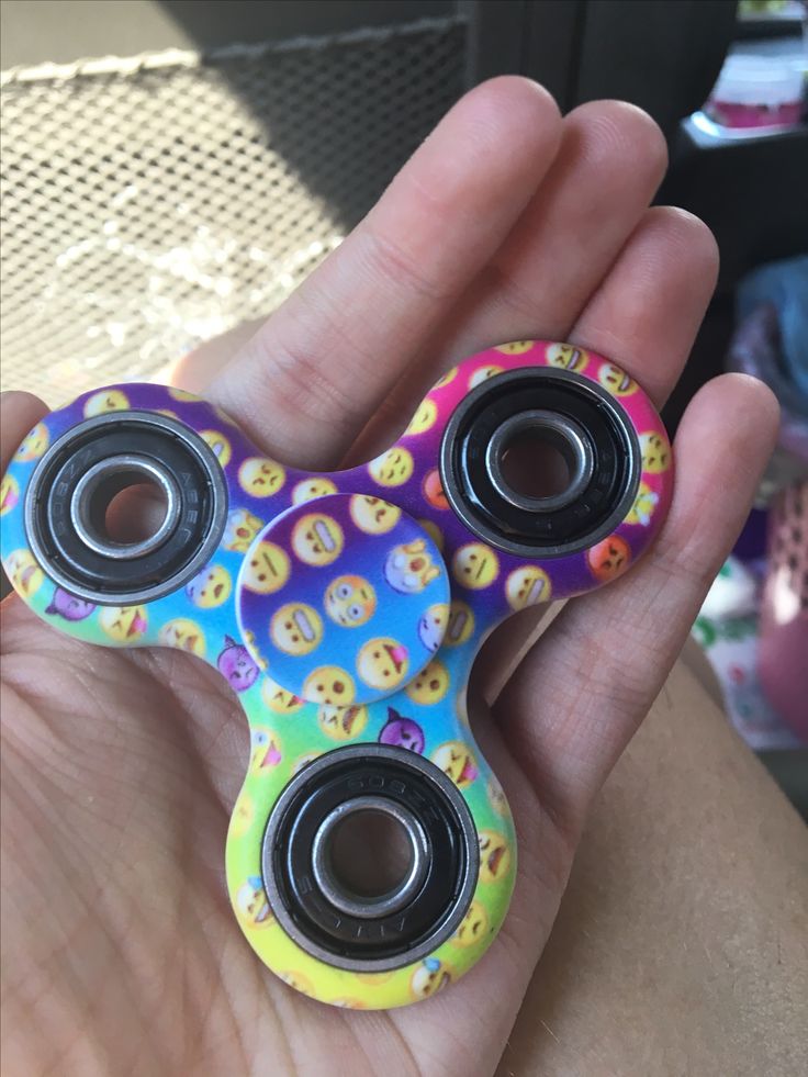 a hand holding a colorful toy with buttons on it's face and two eye holes in the middle