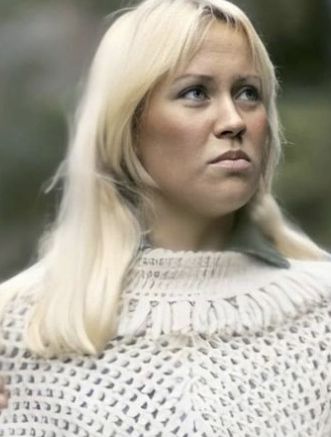 a woman with blonde hair wearing a white sweater and looking off to the side while holding her hand on her hip