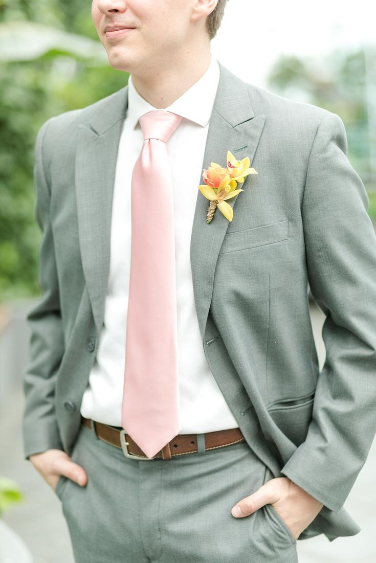 a man in a gray suit with a pink tie and flower boutonniere