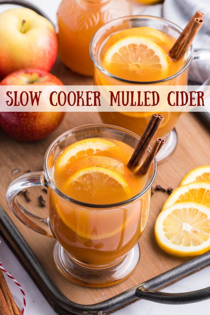 two mugs filled with mulled cider sitting on top of a cutting board