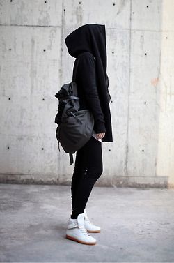 a person wearing a black hoodie and white sneakers with a backpack on their back