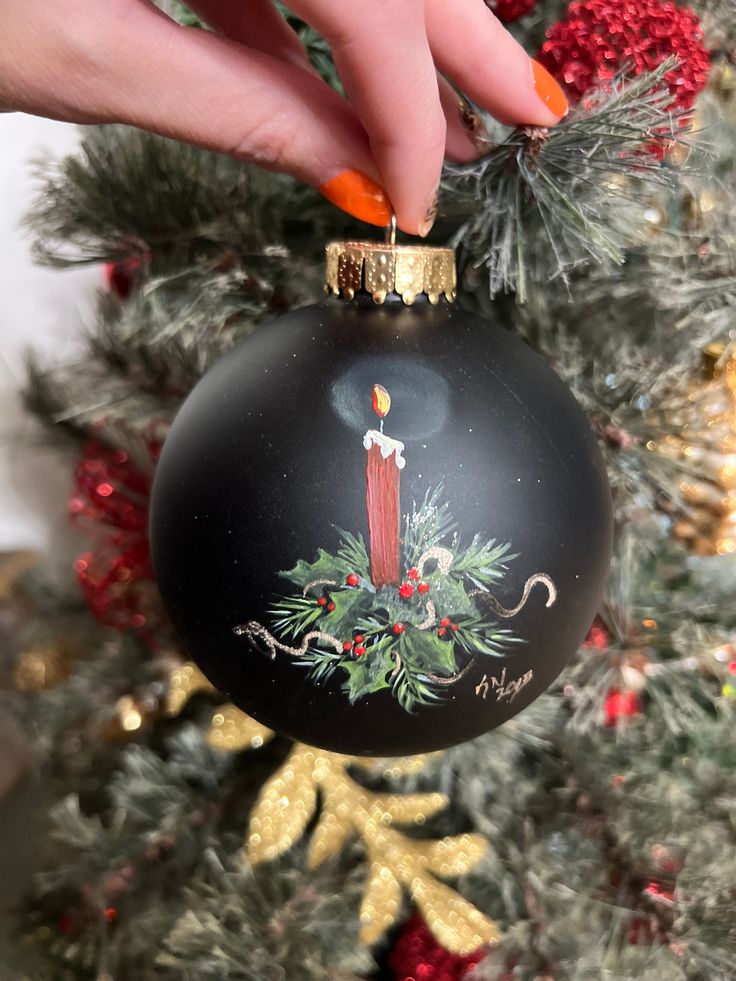 someone is decorating a christmas tree with a candle ornament