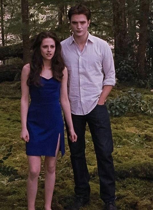 two people standing next to each other in front of trees and grass with one person wearing a blue dress