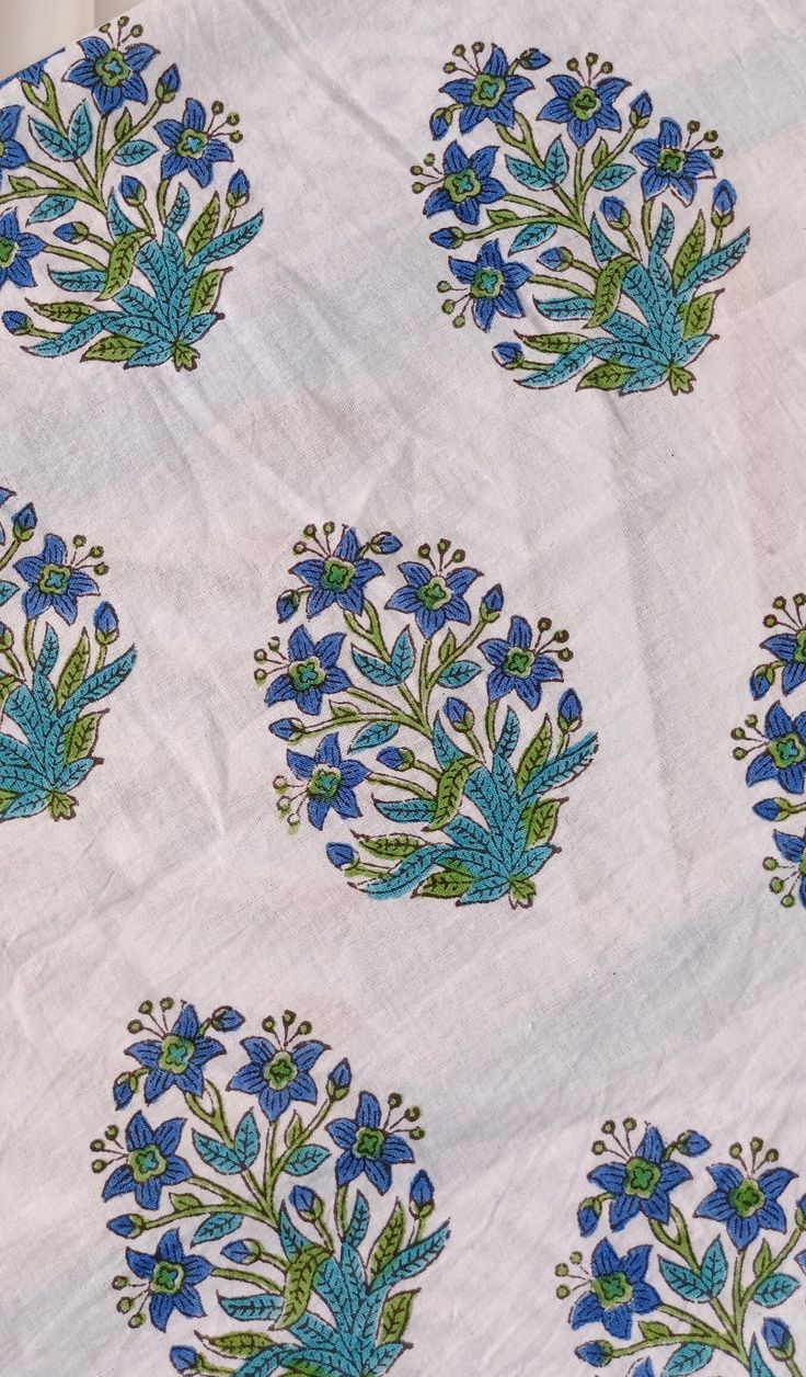 blue flowers and green leaves on white fabric