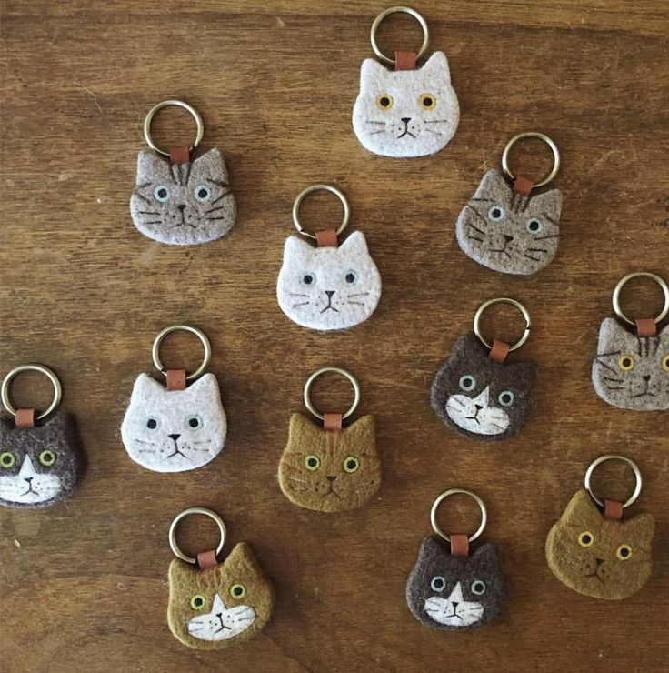 a collection of cat shaped key chains on a wooden table with other cats'heads painted on them