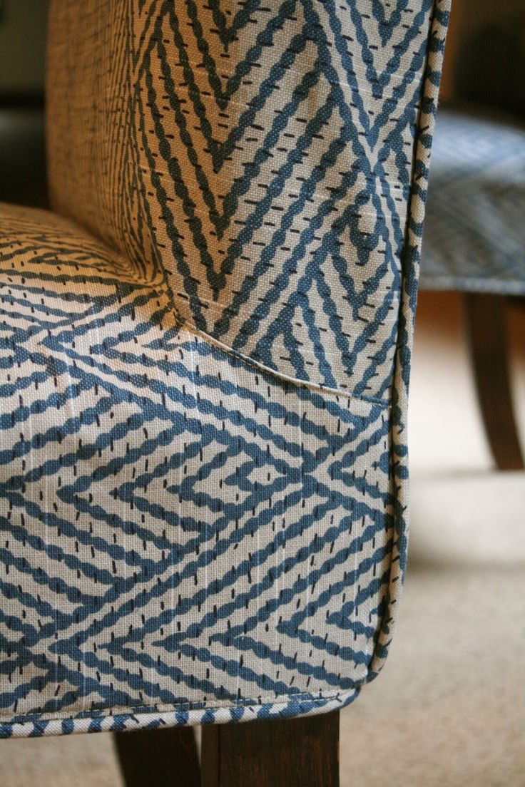 an upholstered chair with blue and white patterns on the back, sitting in a living room