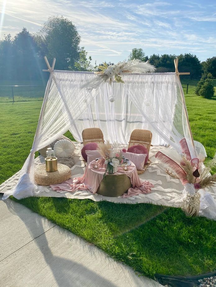 a canopy bed sitting on top of a lush green field next to a picnic table