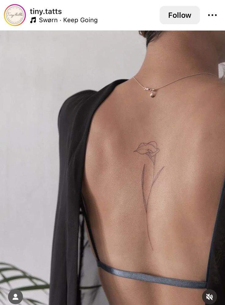 the back of a woman's body with a flower tattoo on her left side